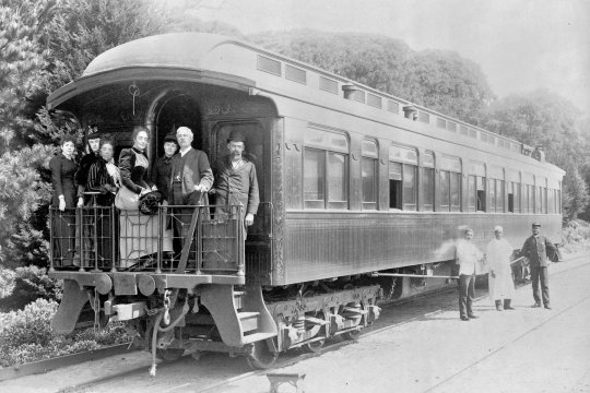 Henry M. Stanley and party standing on back of train at Monterey, California, March 19th, 1891, porters standing at side of car